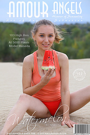 Charming teenage cutie enjoys getting naked and eating a watermelon outside in the dunes.